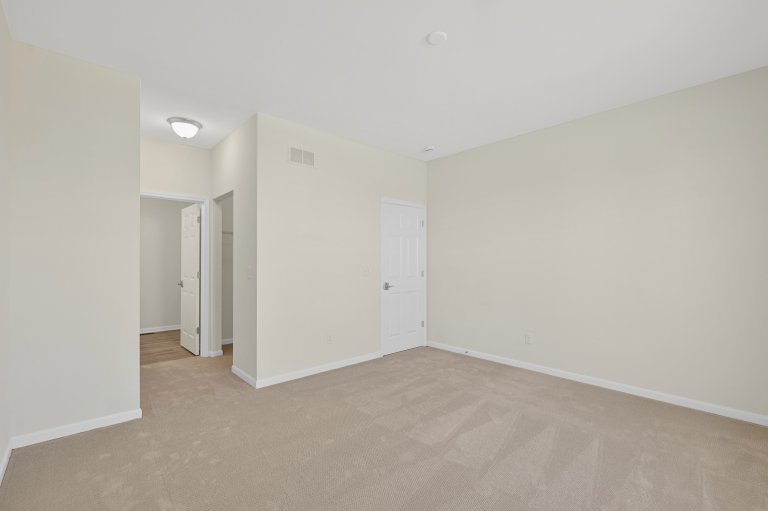 Primary bedroom in the Gerstad Builders Truman new construction home featuring an open layout and private access to the primary bathroom.