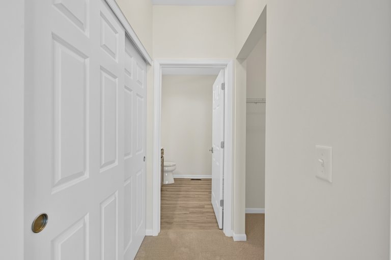 Primary bedroom hallway in the Gerstad Builders Truman new construction home featuring dual closets and private access to the primary bathroom.