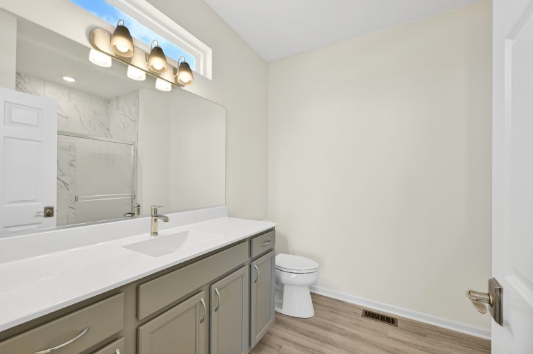 Primary bathroom vanity in the Gerstad Builders Truman new construction home featuring integrated countertop, modern lighting, and open functional layout.