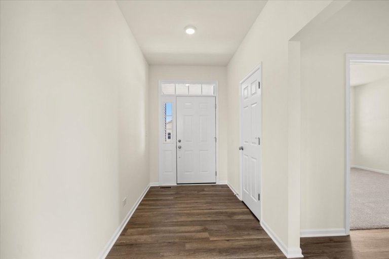 Entryway of the Gerstad Builders new construction home in Northern Illinois featuring luxury vinyl plank flooring, white front door with transom window, and modern open interior design.