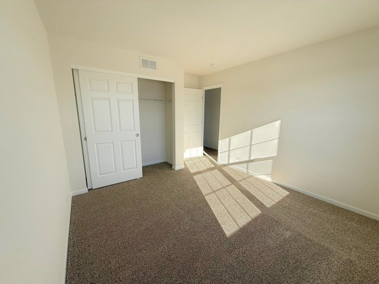 Bright bedroom in new construction home showcasing open floor space, natural light, and modern neutral finishes.