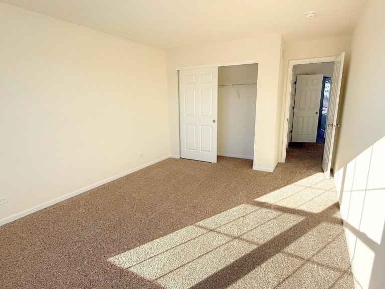 Secondary bedroom in Georgian floor plan featuring large closet, natural light, neutral carpet, and bright layout in a new construction home.