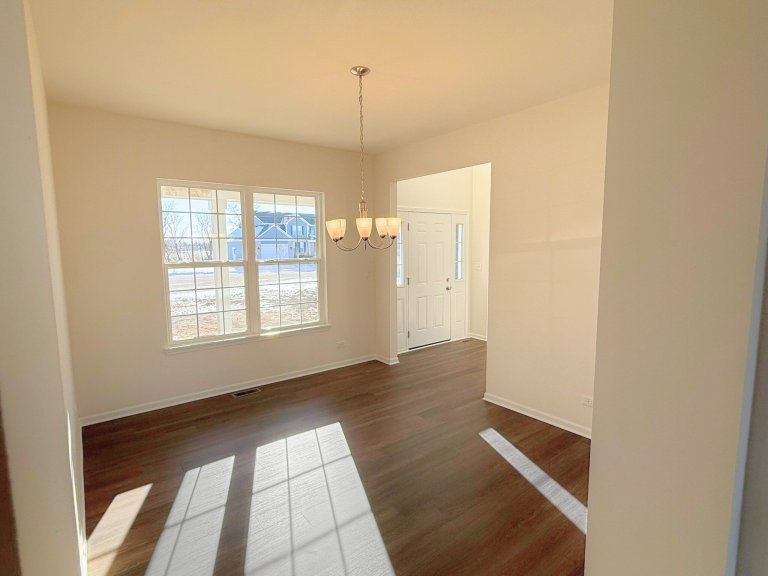 Dedicated dining room in new construction home showcasing open layout, neutral walls, and stylish overhead lighting.