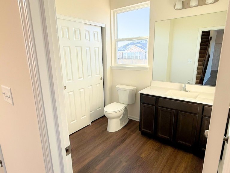 New construction home bathroom showcasing spacious layout, natural light window, and modern vanity storage.