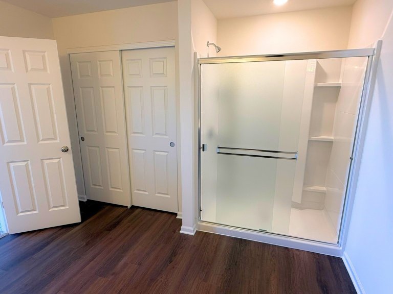 Bright primary bath in model home design showcasing spacious walk-in shower, neutral tones, and durable flooring.