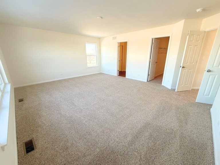 Bright primary suite in Georgian home design showcasing expansive bedroom space, modern finishes, and connected bath.