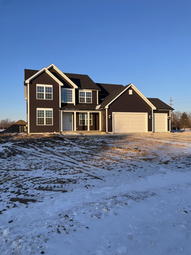 Newly built Georgian floor plan home with open front elevation, multi-gable roof design, and oversized garage in a Midwest new home development.