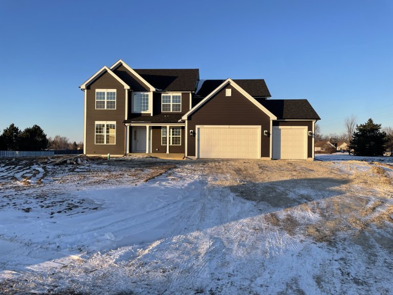 Large Georgian model home exterior featuring modern farmhouse siding, attached 3-car garage, gabled rooflines, and energy-efficient windows on a spacious lot.